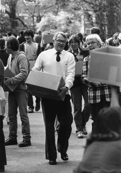 President Charles Glassick carring books to the library