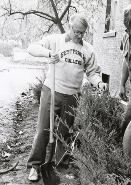 President Charles Glassick planting a shrub
